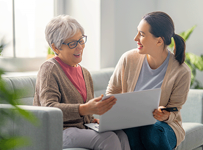 young lady helping senior citizen with laptop and credit card